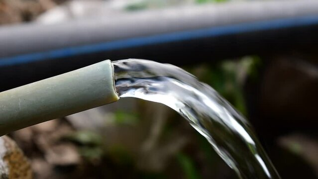 Close shot of fresh water coming out of plastic pipe