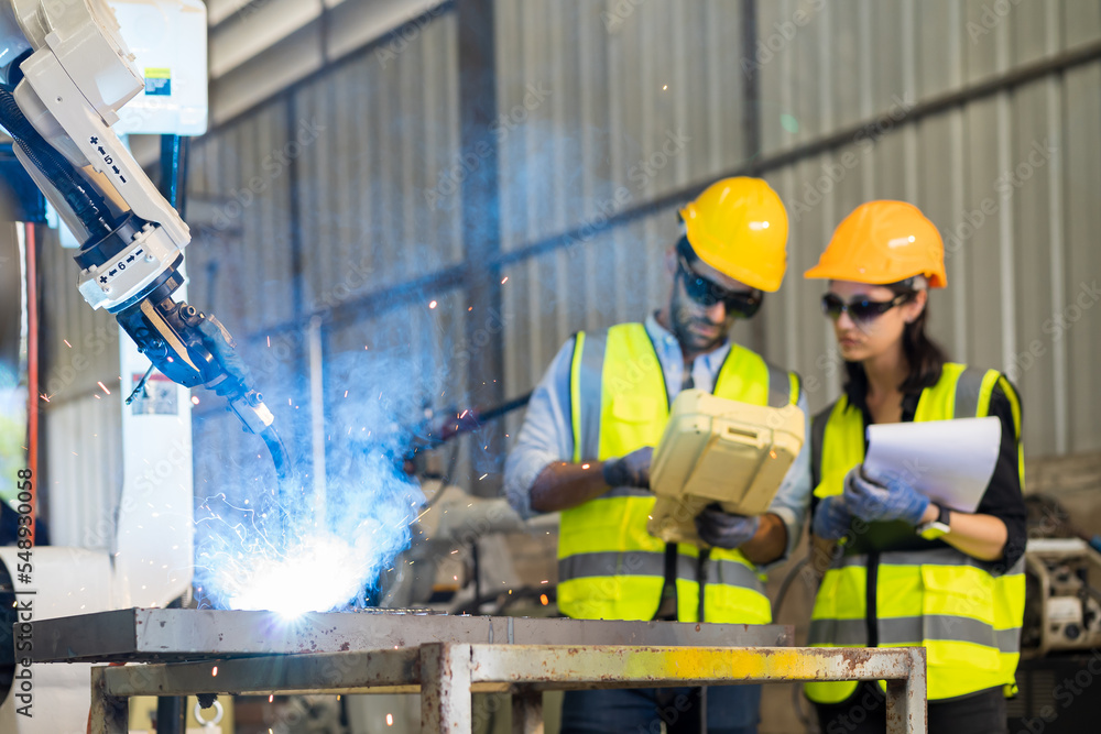 Aufkleber Male engineer and female technician maintenance control robot arm system welding with robot controller at production plant factory. Male and female engineer working with robot arm system welding