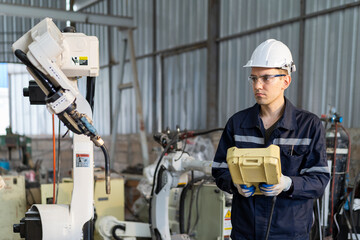 Male engineer using robot controller working with adept robot arm in workshop. Male technician working with control automatic robot arm system welding. Industry robot manufacturing technology