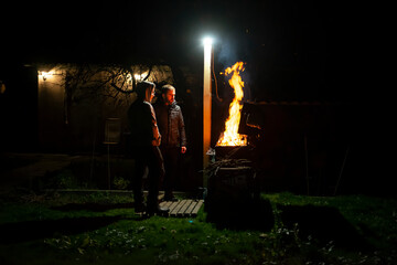 A father and son build a barbecue fire on their plot to cook dinner on an open fire, hey look at the fire and talk.the concept of family values. advertising of insurance companies' services.copy space