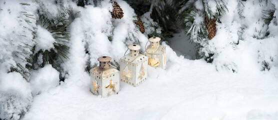 Lanterns in the snow under the Christmas tree