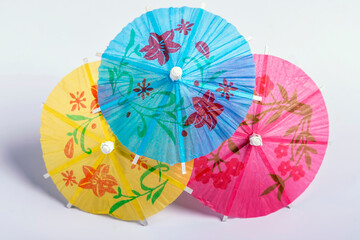 Three decorative paper umbrellas of three different colors against a white background