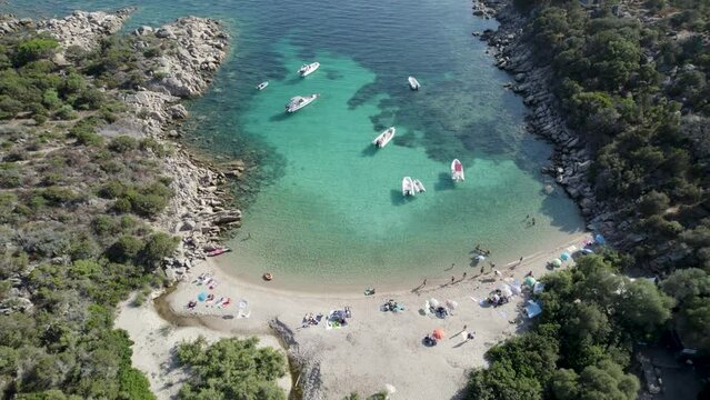Las Cricas cove in Tizzano Beach on French Corsica Island Mediterranean Sea with boats and tourists bathing, Aerial tilt up reveal shot