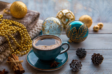 Christmas mood, holiday atmosphere. A cup of coffee, Christmas tree balls, cones, star anise, cinnamon on a wooden windowsill against the background of a window covered with frosty patterns.