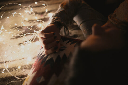 Close up dreaming woman lying near light bulb garland concept photo. Cozy mood. Top view photography with blurred background. High quality picture for wallpaper, travel blog, magazine, article