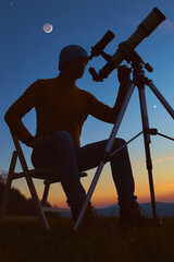 Man with astronomy telescope looking at the night sky, stars, planets, Moon and shooting stars.