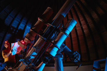 Astronomer with a big astronomical telescope in observatory doing science research of space and...