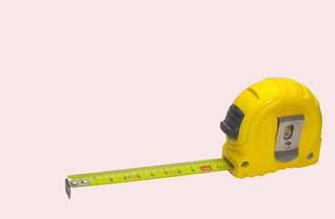 Tape measure on yellow isolated on baby pink background.