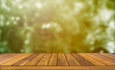 A modern wooden table top outdoor setting contrasts with garden orange sunset blurred background.