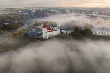 earlier foggy morning and aerial panoramic view on medieval castle and promenade overlooking the old city and historic buildings near wide river
