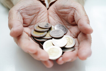 Retired elderly woman counting coins money and worry about monthly expenses and treatment fee payment.