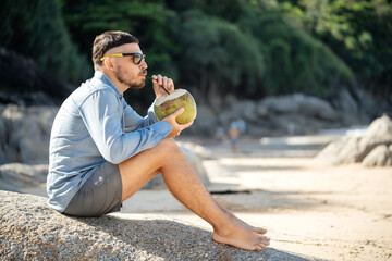 Healthy food in the morning..A man drinks fresh coconut milk on the beach in the morning barefoot...