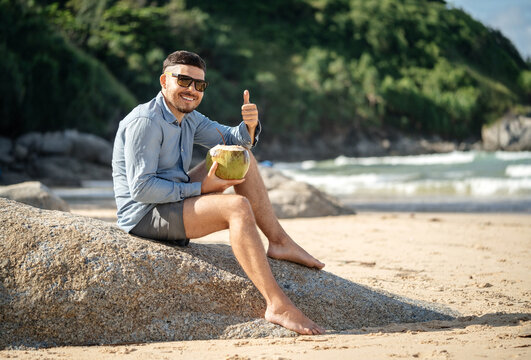 Healthy food in the morning. A man shows a thumbs up gesture. Class! Great! Drink coconut milk in the summer on the beach.
