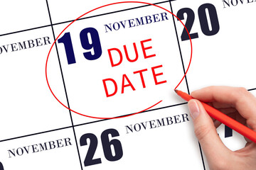 Hand writing text DUE DATE on calendar date November 19 and circling it. Payment due date