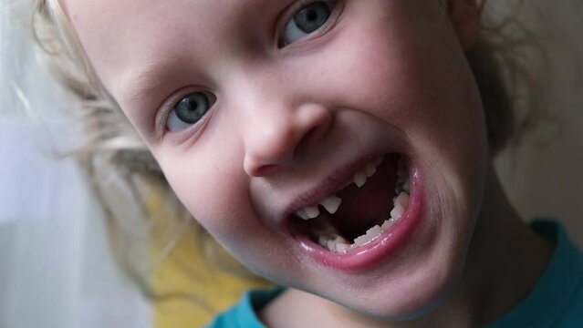 Little blond girl touching and showing milk tooth
