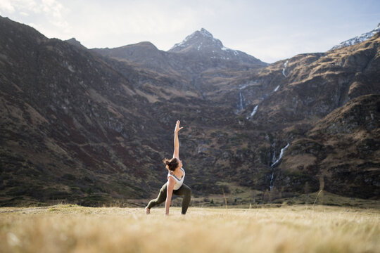 Woman doing yoga triangle pose with bent knee in an alpine meadow, Gastein, Austria