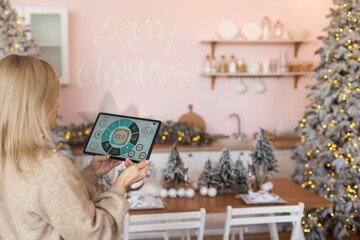 Woman at home using smart screen, automation domestic system at Christmas