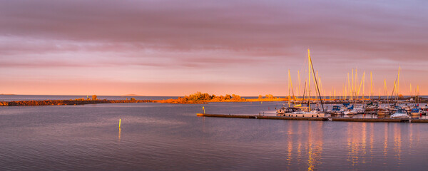 Hafen im Abendrot. Schwedischer Bootshafen, Panoramalandschaft. Segelboote vor Sonnenuntergang.
Harbor in the sunset. Swedish boat harbor, panoramic landscape. Sailboats in front of sunset.