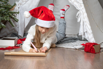Christmas miracle wish list. Christmas helper child writing letter to Santa Claus in red hat....