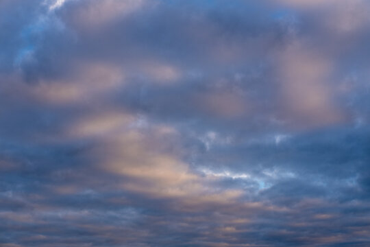 Beautiful sunset or sunrise sky, illuminating dark blue and pale pink clouds. Cloudy sky to overlay on your photos.