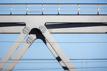 Gray steel truss bridge fragment under blue sky