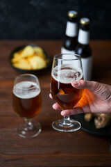 Two glasses with beer, snacks and bottles