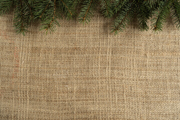 Christmas tree branches, holiday season winter flat lay composition with copy space on jute fabric material.