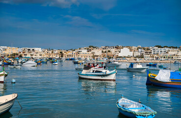 Fototapeta na wymiar View of Traditional fishing boats Luzzu in the Ancient Mediterranean Village of fishermen in Marsaxlokk, Malta