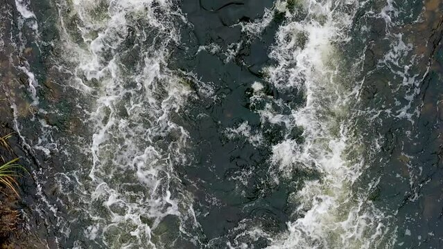 Muddy Water. Dirty Water Flow. Industrial wastewater and foam. Discharge of polluted wastewater into the river. Hazardous waste water. Drone top view shot. Slow motion 120 fps, ProRes 422 video