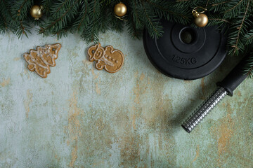 Heavy dumbbell barbell weight plate disc, Christmas cookies and tree branches. Healthy diet...
