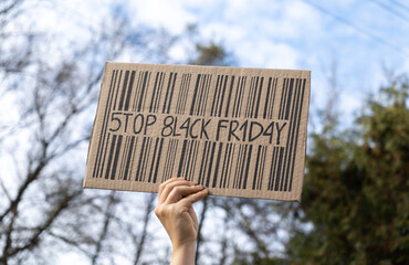 Hand holding sign with slogan Stop Black Friday. Protester with placard at zero waste protest rally. Ecology environmental issues, demonstration against Black Friday Sale, overproduction.