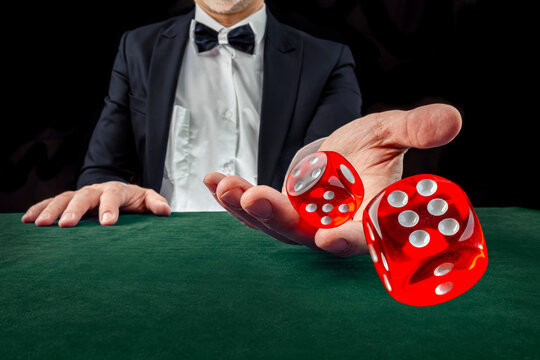 Gambling Concept. Close Up Of Male Hand Throwing Dice At Casino, Gambling Club. Сasino Chips Or Casino Tokens, Poker Cards, Gambling Man Spending Time In Games Of Chance