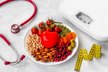 Fat control diet. Healthy food in heart shaped plate with weight scale