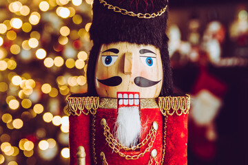 Christmas nutcracker wooden figure. Beautiful, festive toy soldier decoration, with Christmas tree lights bokeh in background.