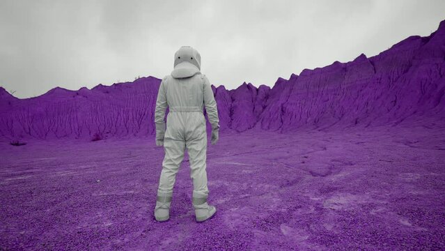 An astronaut in a suit stands on the surface of an exotic pink planet. Epic shot of the new unknown planet with real man.