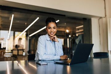 Portrait of a smiling African woman, posing for the camera, being at the office.