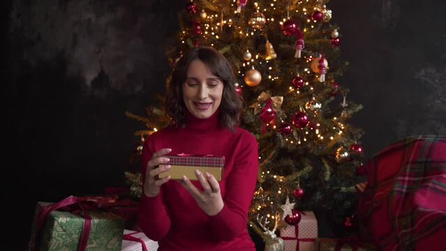 woman with disappointment opening box with surprise on background of xmas tree