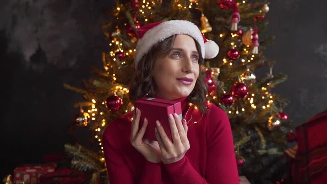 woman looks at a box with a gift, shakes it, tries to guess what is inside