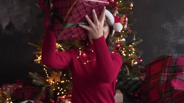 woman looks at a big box with a gift, shakes it, tries to guess what is inside