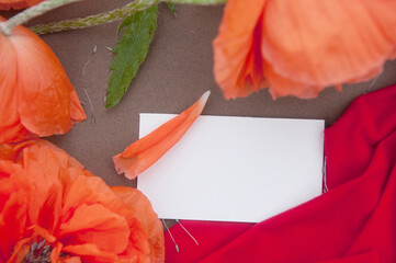 Empty white business card close up mockup with red poppies and gray backdrop, horizontal