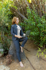 A beautiful freelancer woman works at the park using a computer.