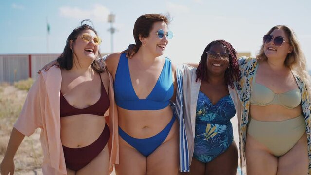 Cinematic storytelling footage of beautiful plus size women having fun at the beach in the summertime. Oversized big girls friends, representation of body positivity and body acceptance concepts