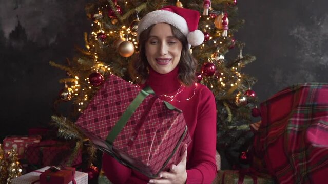 woman looks at a big box with a gift, shakes it, tries to guess what is inside