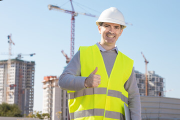 Professional builder standing with notebook in front of the construction site
