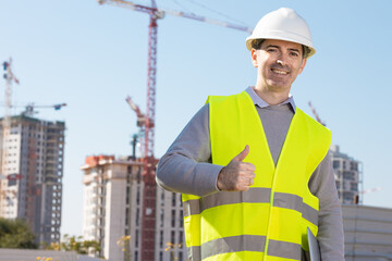 Professional builder standing with notebook in front of the construction site