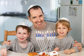 Father and sons with menorah celebrate hanukkah - Jewish religious holiday