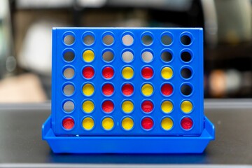 Selective focus shot of a blue Connect 4 game board with yellow and red tokens