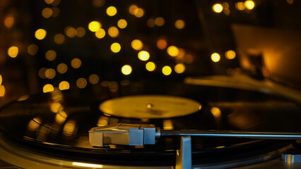 Fototapeta na wymiar Vinyl record player, bright lights bokeh on background. Needle on vinyl record. 