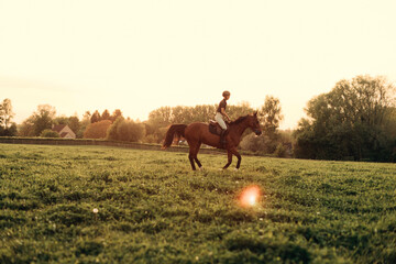 professional horsewoman trotting with her horse at sunset