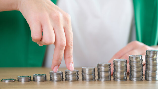 Woman fingers going up on bar chart collected of silver coins